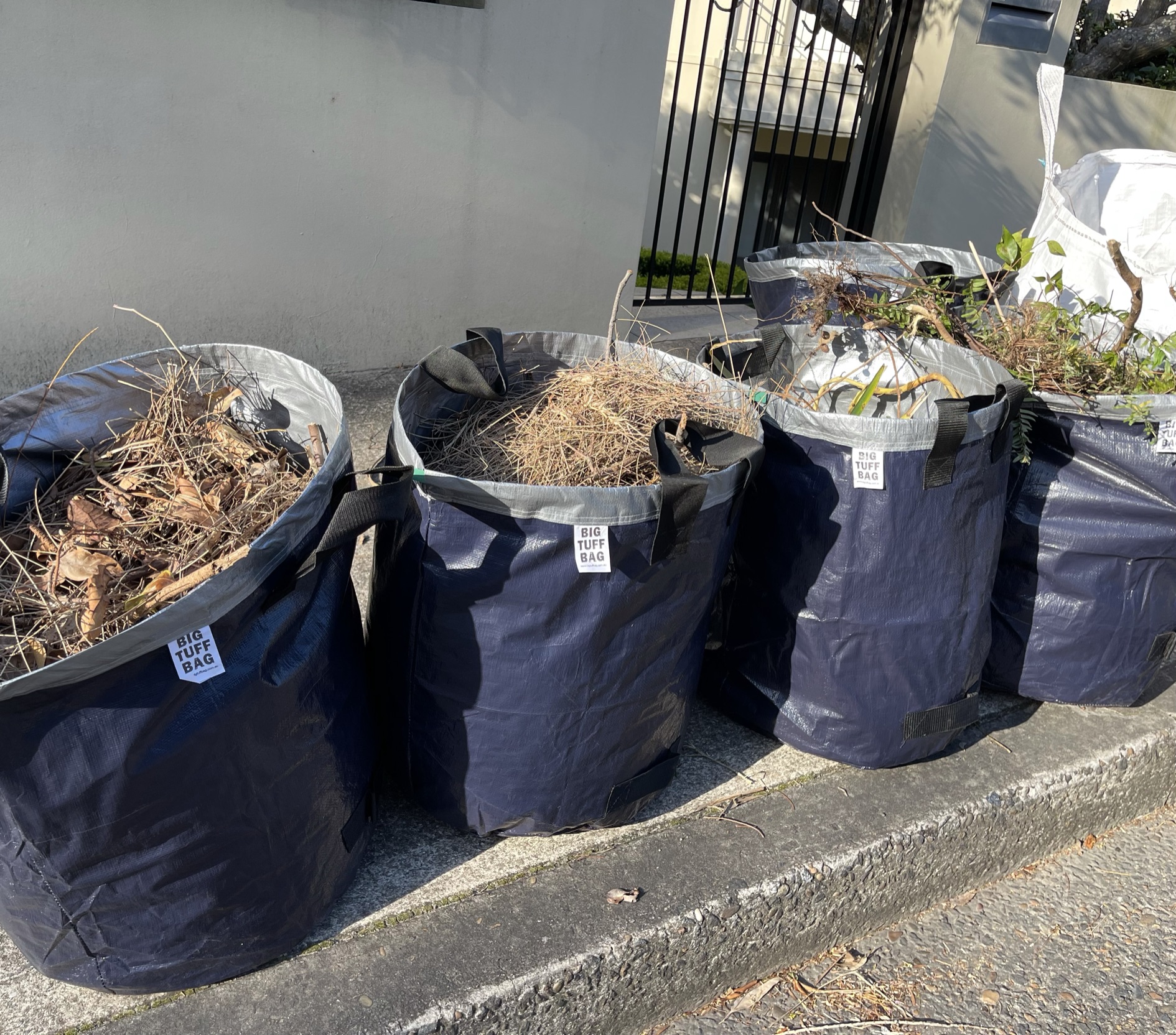 Multiple Big Tuff Bags filled with garden waste on the curbside ready for collection.